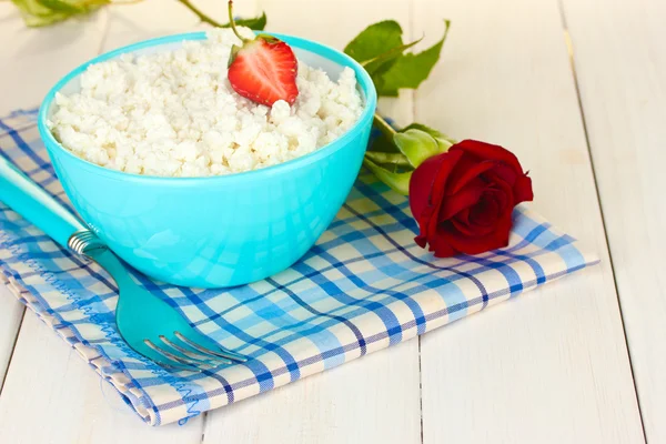 Keso med jordgubbe i blå skål och gaffel på blå rutig servett på vita träbord närbild — Stockfoto
