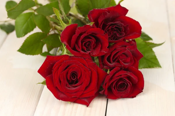 Ramo de rosas rojas en una mesa de madera blanca de cerca — Foto de Stock