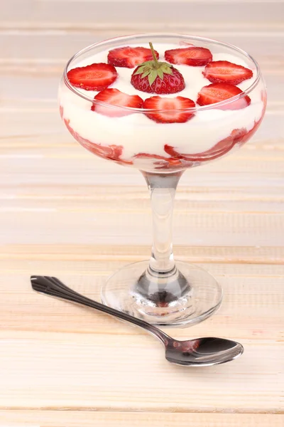 Verre de fraises mûres avec crème sur fond bois — Photo