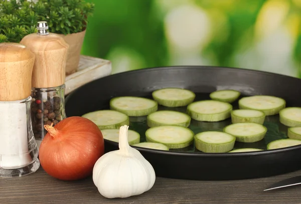 Gesneden pompoen in een pan op houten tafel op groene achtergrond close-up — Stockfoto