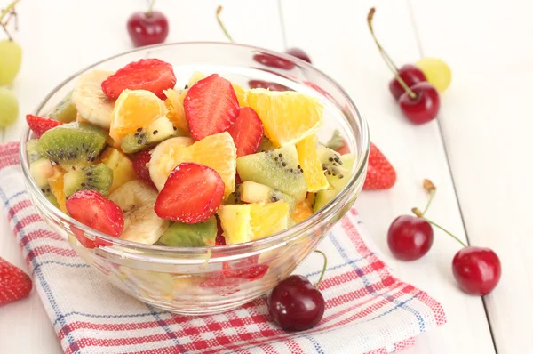 Glazen kom met verse salade fruit en bessen op witte houten tafel — Stockfoto