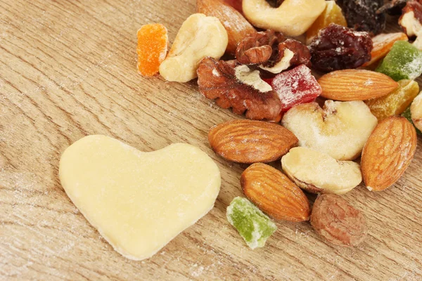Конфеты, орехи, невыпеченные печенья и формы для печенья на деревянном столе крупным планом — стоковое фото