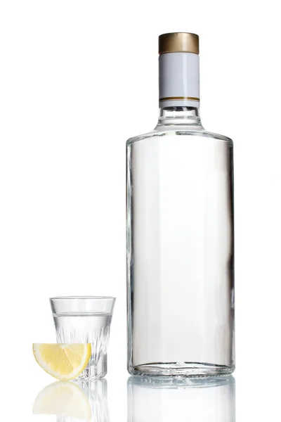 Pullo vodkaa ja viinilasia sitruunalla eristetty valkoinen — kuvapankkivalokuva