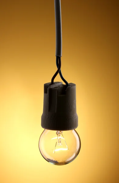 Зажженная лампочка на желтом фоне — стоковое фото