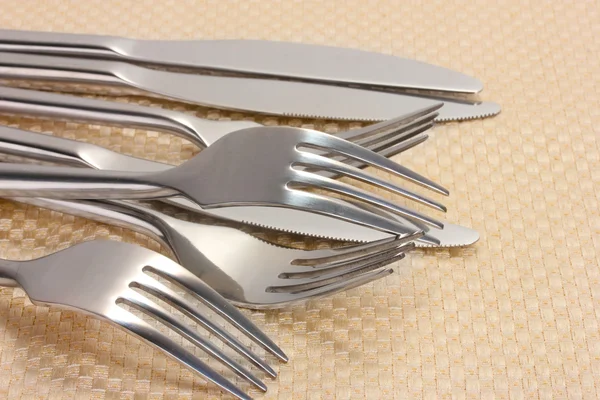 Forks and knives on a beige tablecloth closeup — Stock Photo, Image