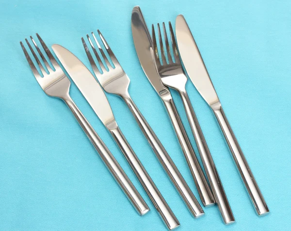 Forchette e coltelli su una tovaglia blu — Foto Stock