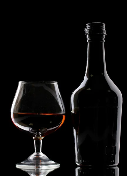 Kieliszek brandy i butelka na czarnym tle — Zdjęcie stockowe