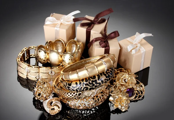 Bellissimi gioielli dorati e regali su sfondo grigio — Foto Stock