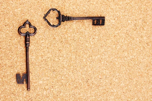 Två antika nycklar på cork bakgrund — Stockfoto