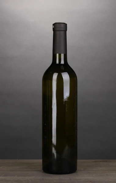 Láhev značkového vína na dřevěný stůl na šedém pozadí — Stock fotografie