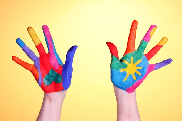 Brightly colored hands on yellow background close-up — Stok fotoğraf