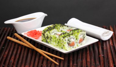 lezzetli rulo ile chopsticks bambu mat siyah arka plan üzerine beyaz tabakta servis