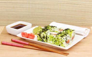 lezzetli rulo ile chopsticks açık renkli ahşap tablo üzerinde beyaz tabakta servis