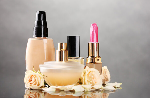 Сosmetics with roses on gray