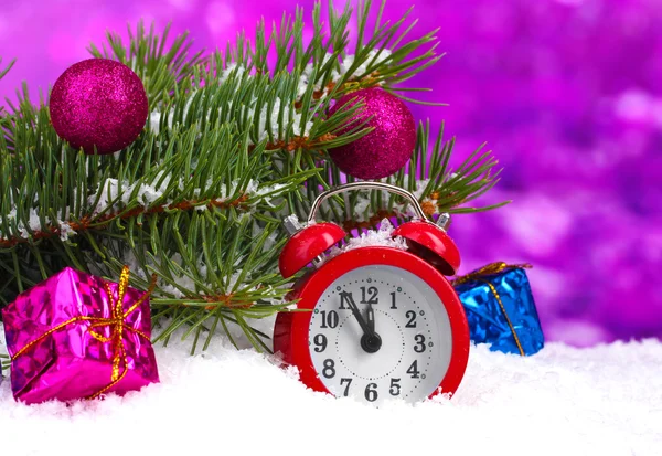 Groene kerstboom met speelgoed en klok in de sneeuw op paars — Stockfoto