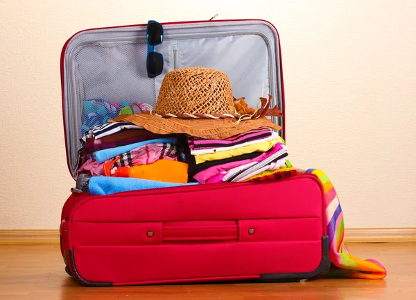 Valigia rossa aperta con indumenti in camera — Foto Stock