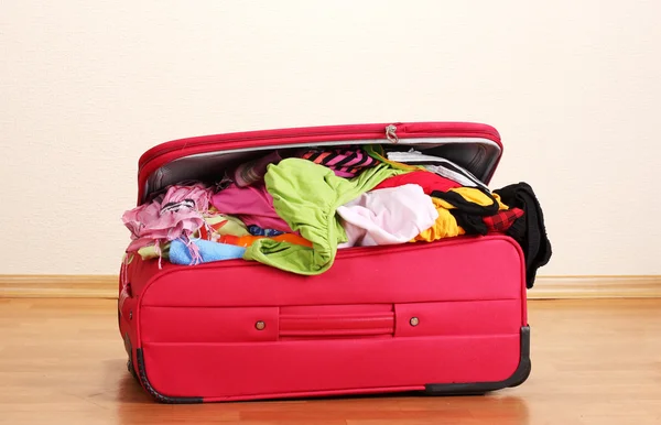 Verschlossener roter Koffer mit Kleidung im Zimmer — Stockfoto