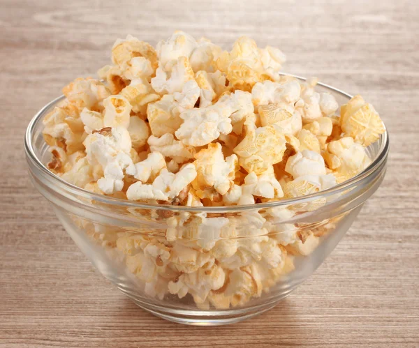 Popcorn in glass bowl on wooden table — Stock Photo, Image