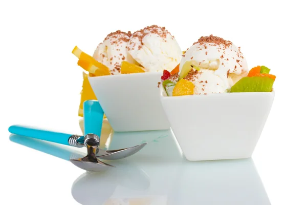 Вкусное ванильное мороженое с шоколадом и фруктами в мисках и ложках, изолированных на белом — стоковое фото