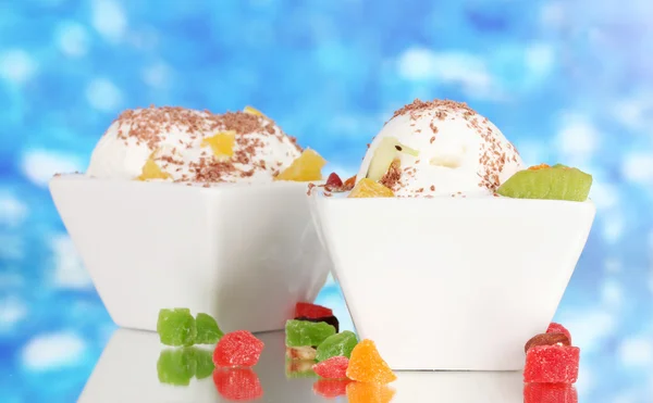 Leckeres Vanilleeis mit Schokolade und Früchten in Schalen auf blauem Hintergrund — Stockfoto