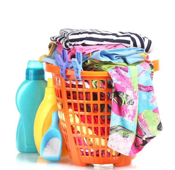 Одежда с моющим средством и стиральным порошком в оранжевой пластиковой корзине изолированы на белом — стоковое фото