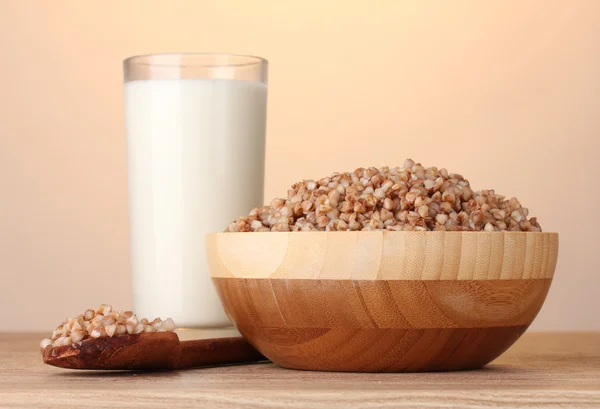 Vařená Pohanka v dřevěné misce se sklenicí mléka na dřevěný stůl na hnědé — Stock fotografie