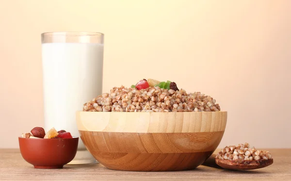 Trigo sarraceno hervido en un tazón de madera con un vaso de leche sobre una mesa de madera sobre marrón — Foto de Stock