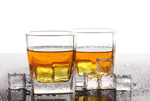 スコッチ ウイスキーと白で隔離されるテーブル上の氷の 2 つのメガネ — ストック写真