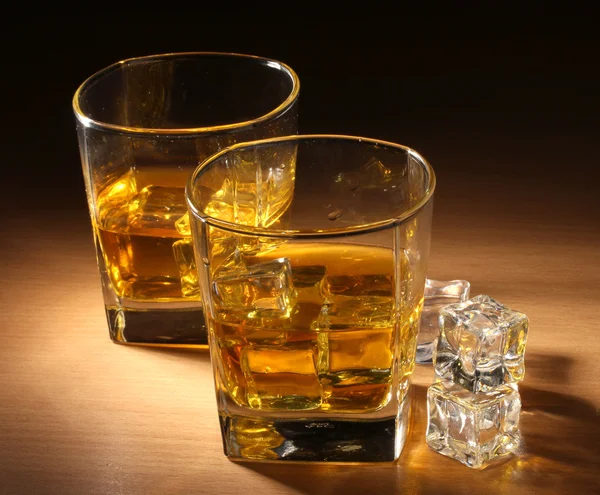 Two glasses of scotch whiskey and ice on wooden table — Stock Photo, Image