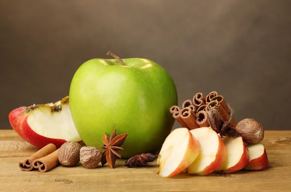 Laski cynamonu, jabłka, gałka muszkatołowa i anyżu na drewnianym stole na brązowym tle — Zdjęcie stockowe