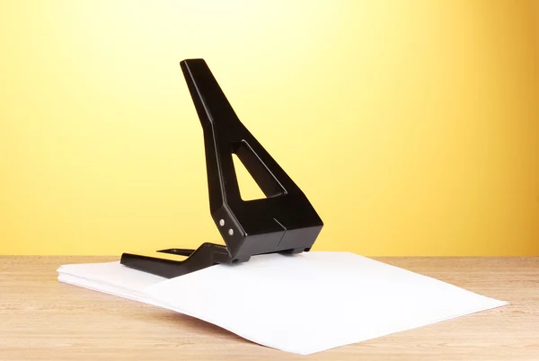 Black office hole punch with paper on yellow background — Stock Photo, Image