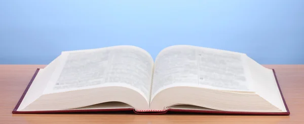 Buch aufschlagen auf Holztisch auf blauem Hintergrund — Stockfoto