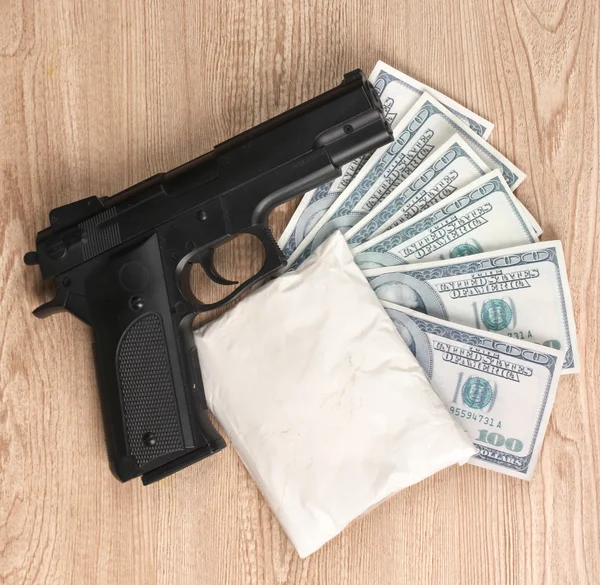 Cocaïne in pakket, dollars en pistool op houten achtergrond — Stockfoto