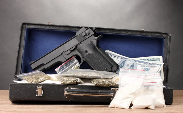 Kokain, Marihuana-Dollar und Handfeuerwaffe im Koffer auf Holztisch vor grauem Hintergrund — Stockfoto