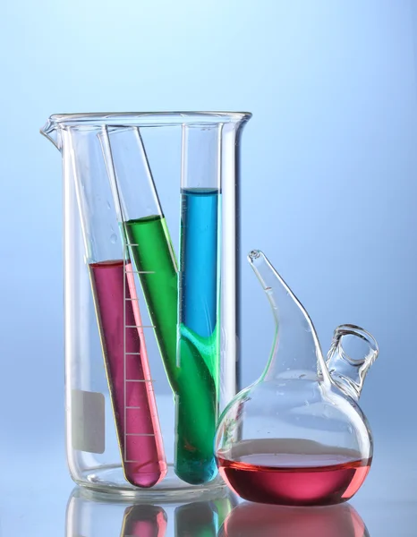 Лабораторний скляний посуд з кольоровою рідиною та відображенням на синьому фоні — стокове фото