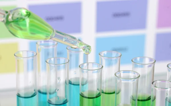 Test-tubes with color liquid and pipette on color samples background — Stock Photo, Image