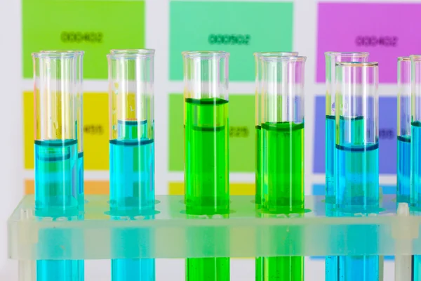 Tubos de ensayo con líquido de color sobre fondo de muestras de color — Foto de Stock