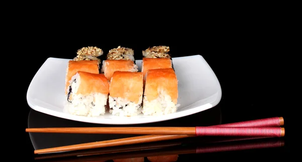 Rotoli gustosi serviti su piatto bianco con bacchette isolate su nero — Foto Stock