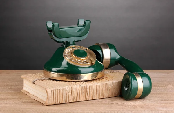 Retro telefon stojící na knihu na dřevěný stůl na šedém pozadí — Stock fotografie