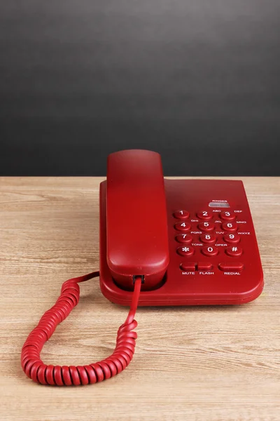 Red phone on wooden table on grey background — Stock Photo, Image