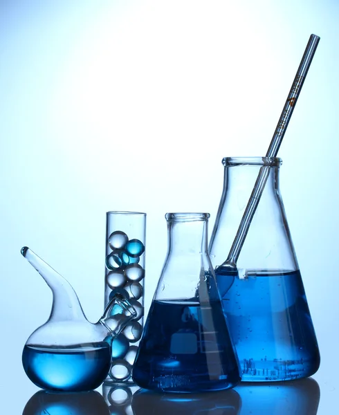 Reagenzgläser mit blauer Flüssigkeit auf blauem Hintergrund — Stockfoto
