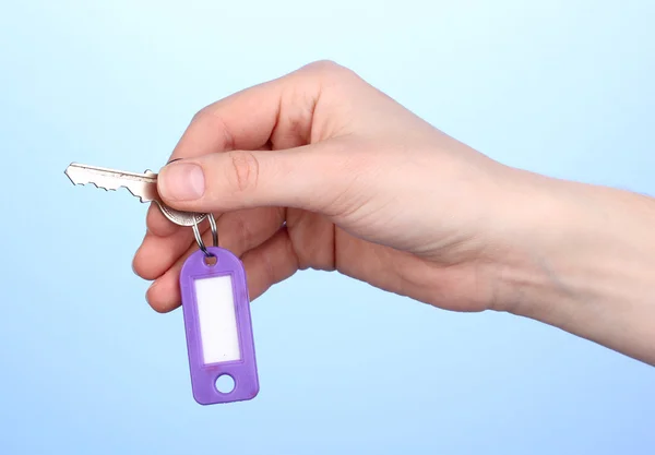 Schlüssel in der Hand auf blauem Hintergrund — Stockfoto