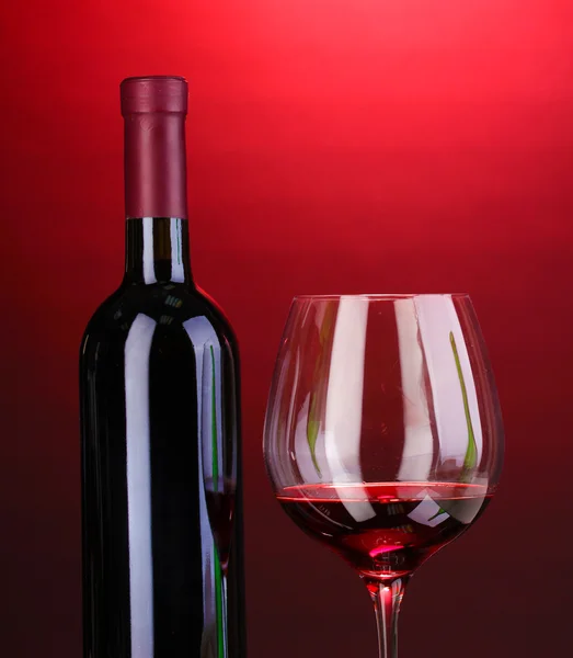 Garrafa de grande vinho e vinho no fundo vermelho — Fotografia de Stock
