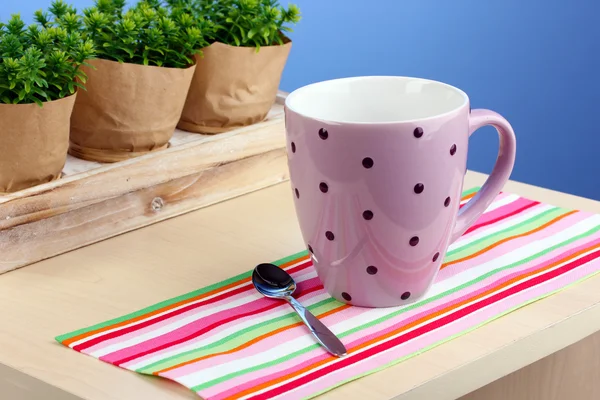 Taza de café en la mesa en la cafetería sobre fondo azul — Foto de Stock