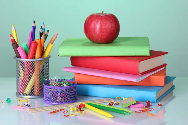 Složení knihy, papírnictví a apple na zářivě barevné pozadí — Stock fotografie