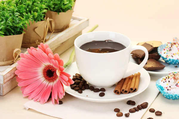Tasse de café et gerbera haricots, bâtonnets de cannelle sur table en bois — Photo