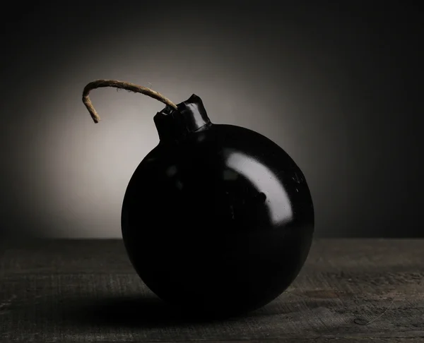 Bomba in stile cartone animato su tavolo di legno su sfondo nero — Foto Stock