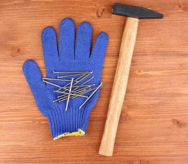 Hammare och handsken på trä bakgrund — Stockfoto