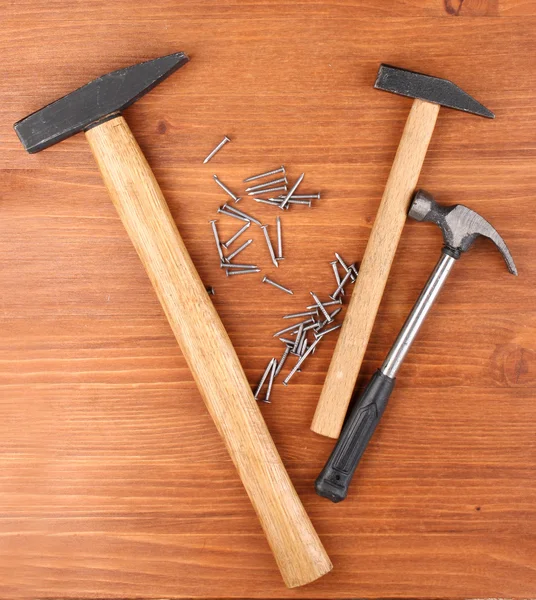 Martelos e pregos de metal no fundo de madeira — Fotografia de Stock
