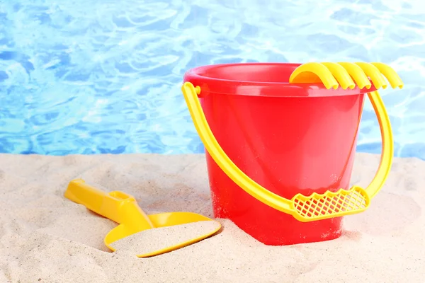 Детские пляжные игрушки на песке на водном фоне — стоковое фото